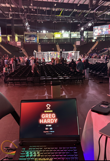 Fight Judge AI cage-side laptop displaying a live winner result surface in an active arena.